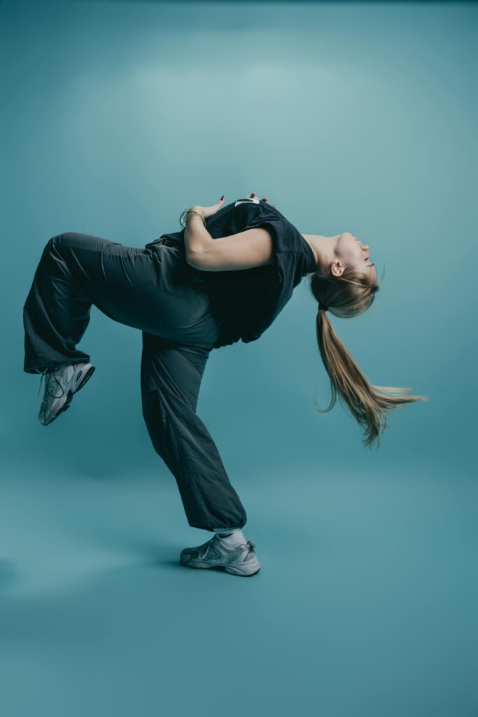 Young dancer captures motion in a dynamic pose with motion against a monochrome blue background.